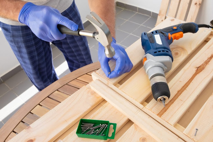 Tradesperson assembling timber outdoor furniture with a hammer and drill