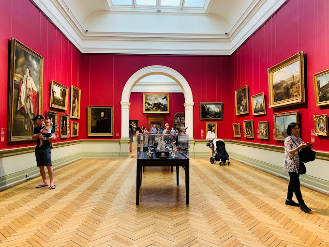 Gallery room at the Art Gallery of New South Wales with paintings hung on red walls