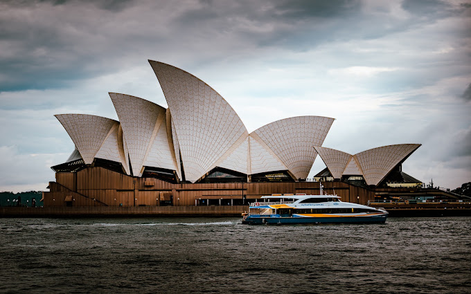 Sydney Opera House sails viewed from the harbour with a ferry passing by